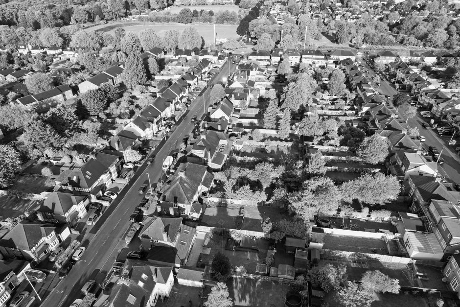 Aerial view of residential houses and gardens in East Dulwich with tidy, well-maintained surfaces. The rooftops and gardens display a mix of tiled, flat, and shingled surfaces, some with visible outdo